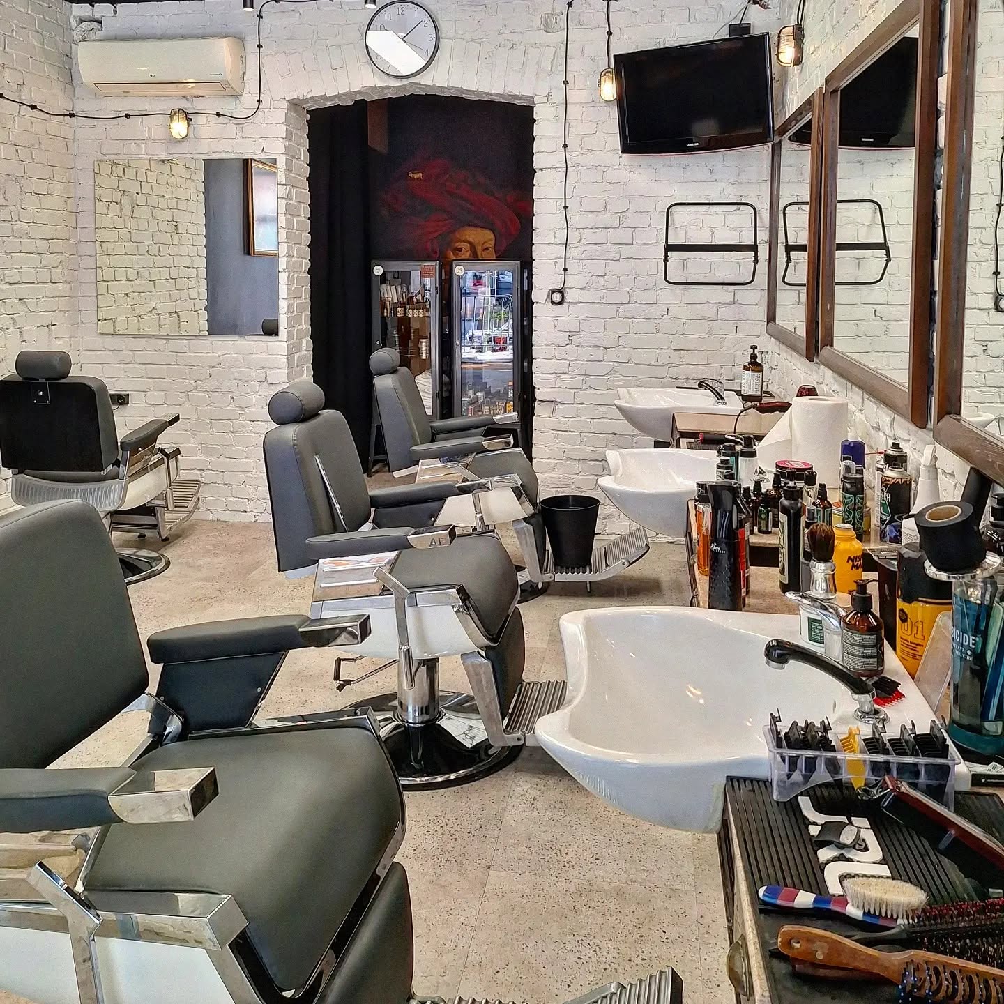 Wnętrze The Barbers — biała cegła i fotele barberskie